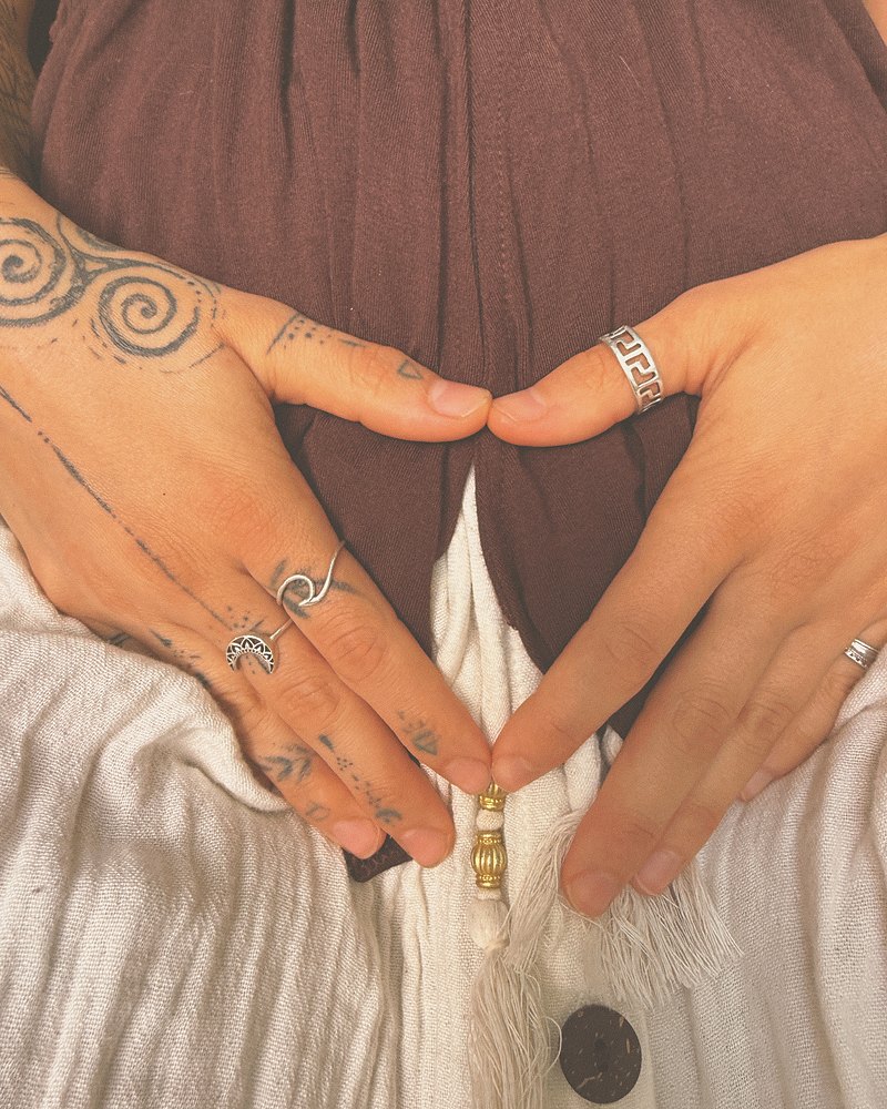 Two hands resting low over the belly, fingers meeting in a downward triangle.